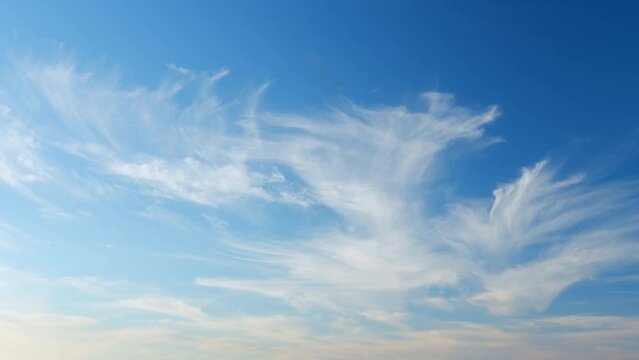 Floating fluffy cirrus clouds. Beautiful sunny blue sky with wispy smoky white. Timelapse.