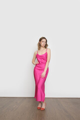 Woman in pink silk satin camisole dress, studio shot.