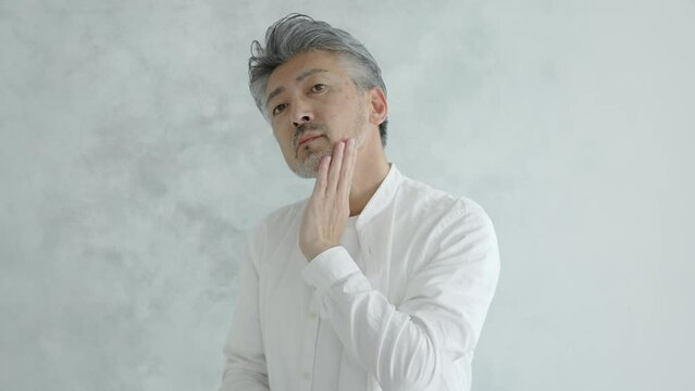 ヒゲの手入れをするシニア男性