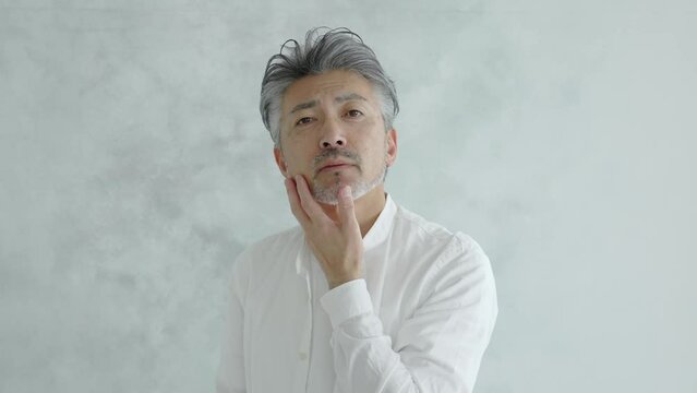 ヒゲの手入れをするシニア男性