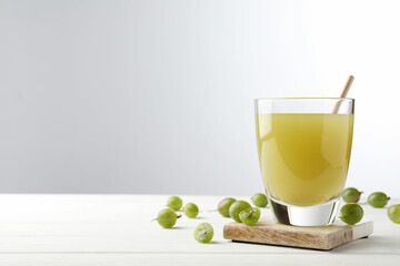 Tasty gooseberry juice on white wooden table against light background. Space for text