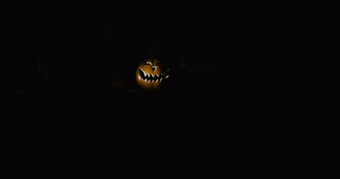 Halloween pumpkin in the dark vintage room, spotlight over the top | camera in movement from left to right panorama wide shot | 4k 12-bit footage 