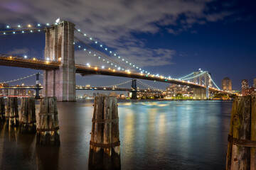 Evening view of the Brooklyn Bridge and Manhattan Bridge and wood pilings. View of East River and Dumbo in Brooklyn, New York City - 541345945