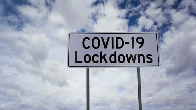 Timelapse clouds with a road sign that says COVID-19 Lockdowns signifying an epidemic or outbreak that requires drastic measures to control it.