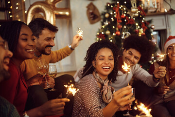 Multiracial group of happy friends using sparklers and having fun on New Year's day at home.