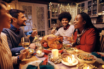 Two happy couples talking during Thanksgiving meal in dining room.