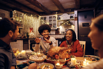 Fototapeta na wymiar Young happy friends enjoy in conversation during Christmas dinner at dining table.