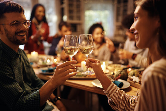Close up of couple toasting during Thanksgiving lunch with friends.