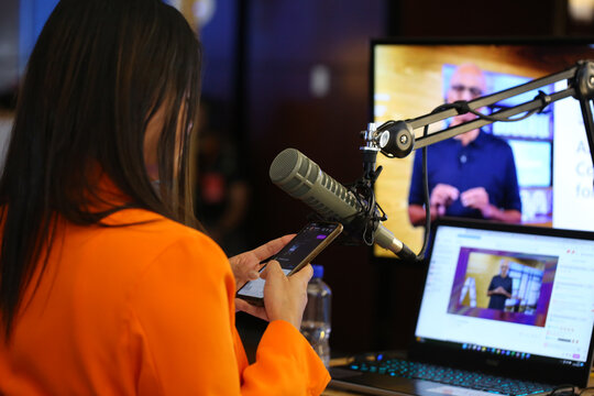 presenter broadcasting her podcast live with a professional microphone and headphones in a small broadcasting studio streaming