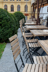 Restaurant patio with empty chairs and tables. Open terrace with wooden furniture without people.