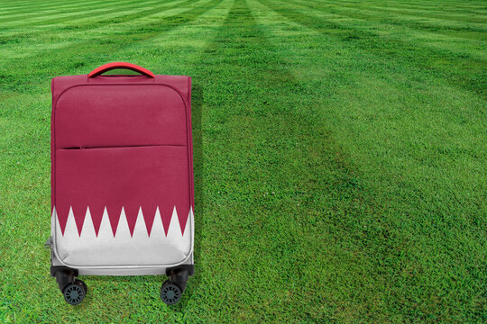 Bag painted with the colors of the Qatari flag on a soccer field. Travel concept. World cup 2022.