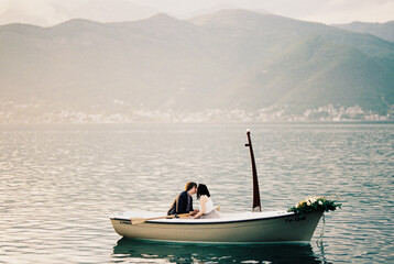 Man and woman kiss in a boat in the sea