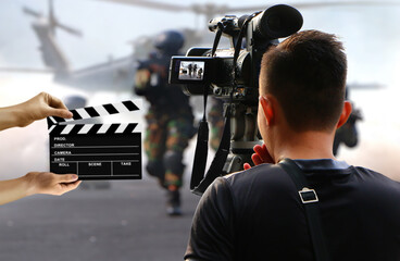 Production cameraman shooting an action movie with hands holding clapper board in background