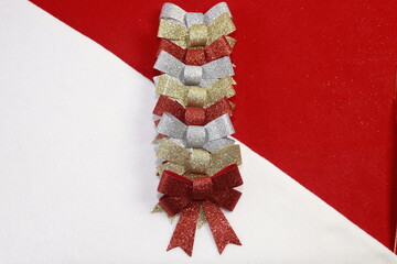 Conjunto de mo&ntilde;os en color carmes&iacute;, oro y plata formados en una linea frente a un fondo bicolor blanco y rojo