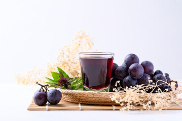 Black grape and juice in glass on white background, healthy drink