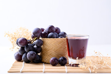 Black grape and juice in glass on white background, healthy drink