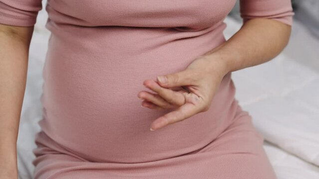 close up of pregnant woman checking blood sugar level by herself with glucose meter at home. gestational diabetes concept.