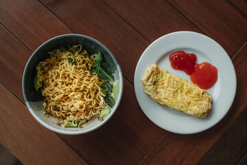 A bowl of instant noodle and omelette in the wooden table