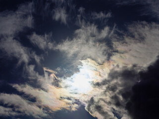 The sun shines into overcast dark yellow-blue clouds
