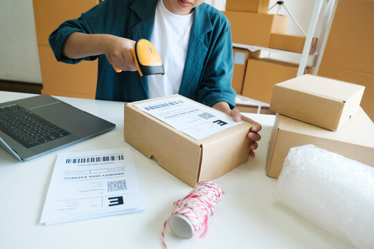 Young entrepreneur scanning online order box.