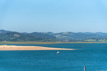 Fototapeta na wymiar Vista panorámica de la bahía de Santoña durante la marea baja con el agua del mar en calma y turquesa y la arena blanca durante un día soleado con el cielo azul despejado en Cantabria.