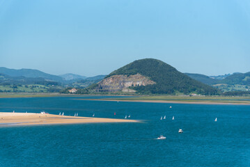 Fototapeta na wymiar Vista panorámica de la bahía de Santoña durante un día de verano soleado con el mar en calma y el agua turquesa, y al fondo el monte La Arenilla en Cantabria.