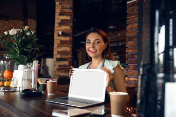 Young business owner with laptop at table in her cafe