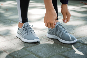 Young woman tying shoe lace outdoors, closeup