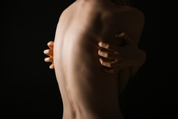Back of young woman on dark background. Anorexia concept - obrazy, fototapety, plakaty