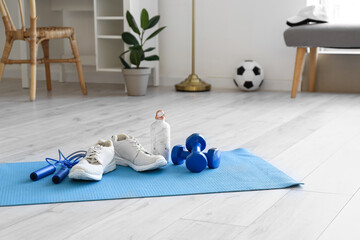 Sport equipment and sneakers on floor mat in light room