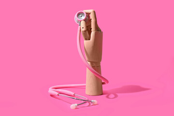 Wooden hand with stethoscope on pink background