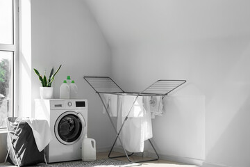 Interior of light laundry room with washing machine, basket and dryer