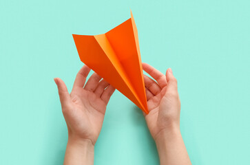 Woman with orange paper plane on color background