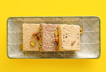 Plate with pieces of tasty sesame halva on yellow background