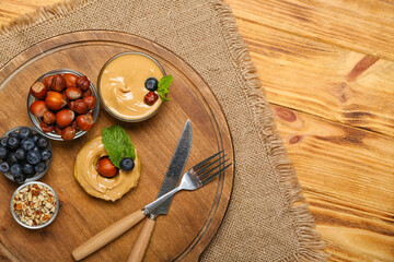 Board with tasty apple round, nut butter, blueberry and hazelnuts on wooden table