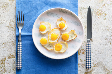 Plate with tasty fried quail eggs on light background