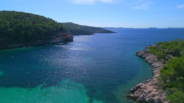 View over bay from villa to beach 
Smooth aerial view flight rotation to left drone
of Ibiza cala Salada Saladeta beach at summer 2022. 4k marnitz Cinematic