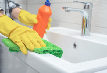 Man doing chores cleaning bathroom at home. Cropped view of woman in rubber gloves wet rag near...