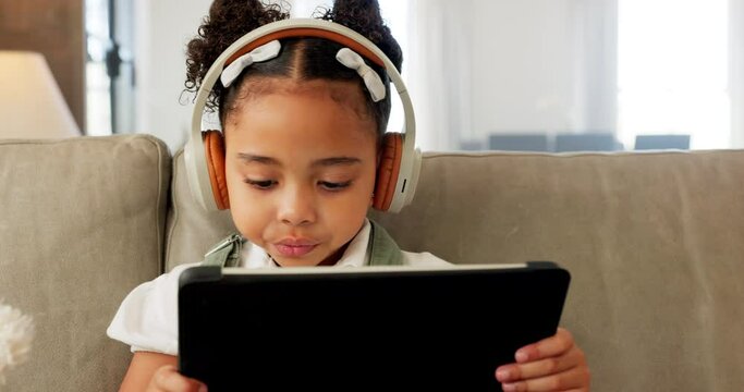 Tablet, headphones and child with e learning app, watch video on website for kids or online education on sofa at home. Girl listening to audio ebook, music or digital video games on living room couch
