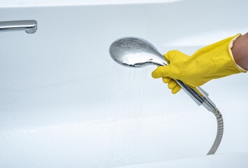 Person using hand held shower head. gloved hand holding shower head. hand holds shower head with...