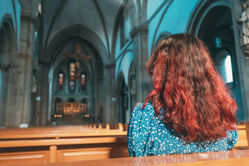 The girl prays in the Catholic Church and asks God for health, forgiveness of sins and finding...