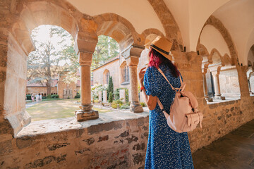 A girl traveler and tourist in the arch of an ancient monastery or the courtyard of the cathedral