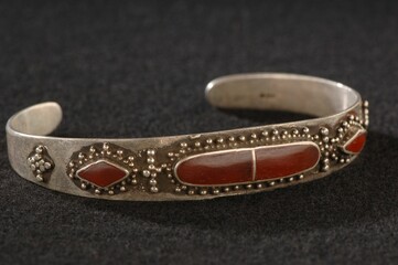 Antique, elegant bracelet with engraving and precious red stones isolated on a black background