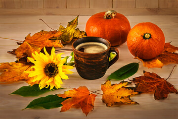 Vintage cup of coffee, orange pumpkins, autumn leaves and sunflower on a wooden light background. Composition for Halloween.