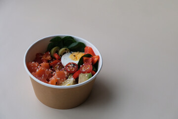 Takeaway poke bowl with fresh salmon, avocado, quinoa and vegetables in recycled kraft paper packaging. Healthy Trendy Fitness food.