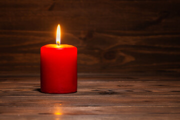 burning candle on wooden background in minimalist room interior, copy space