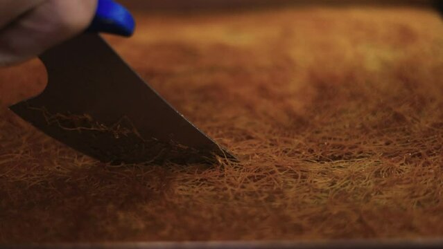 Pastry chef cutting the kadaifi pastry with a knife in the large pan