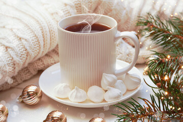 Obraz na płótnie Canvas Winter, Christmas, New Year decorations composition, concept, background. White Mug, cup of tea, coffee, steam, meringue, knitted plaid. Christmas lights. Christmas mood morning. Christmas card.