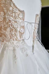 A beautiful wedding dress hangs on a mannequin in the room. Preparation and conduct of the wedding.