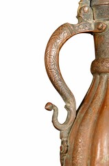 Close up of a handle of an antique copper jug with artistic chasing and engraving